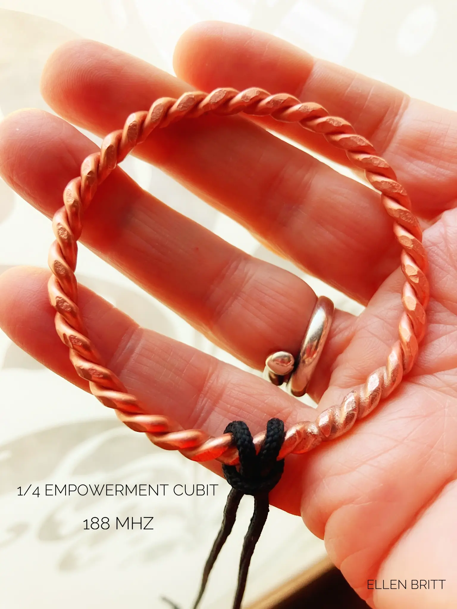 1/4 Empowerment Cubit copper tensor ring held in palm, 188 MHz